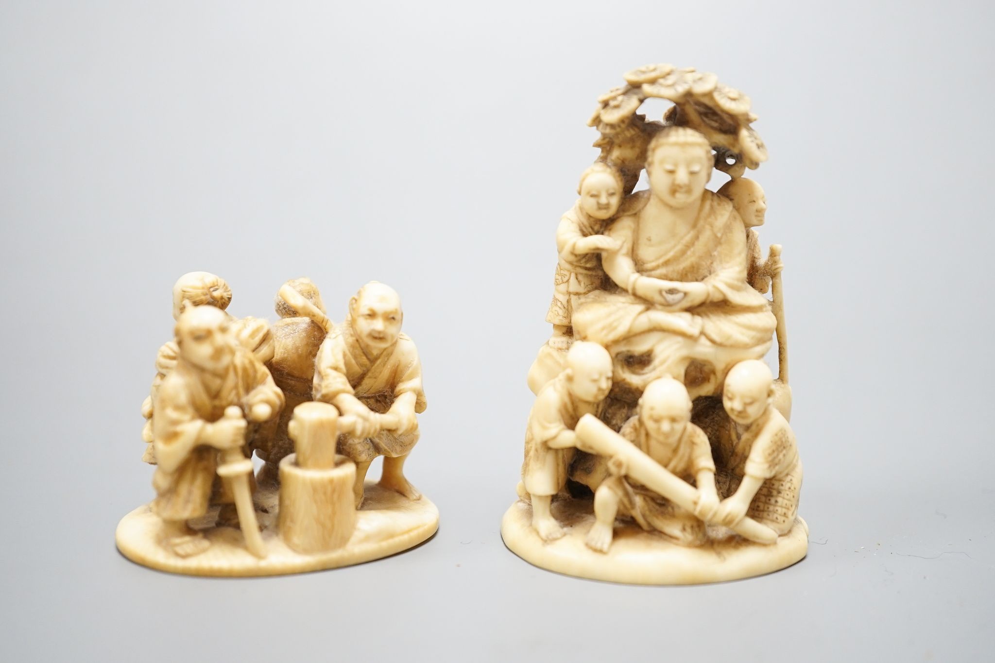 Two Japanese ivory okimono-netsuke of Buddha and attendants and a group of artisans, Meiji period, both signed, tallest 7cm